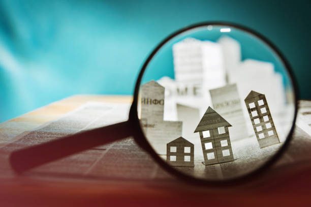 A magnifying glass showing paper buildings popping out of a newspaper